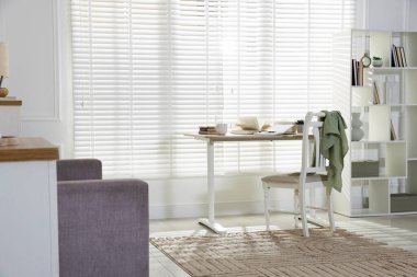 Oturma odasının penceresinin yanındaki tahta masa, sandalye ve raf ünitesi. İç tasarım