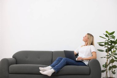 Evdeki kanepede dizüstü bilgisayarı olan kadın. Metin için boşluk