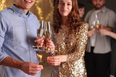 Yeni yılı evde maytap ve şarap kadehleriyle kutlayan arkadaşlar, seçici odaklanma