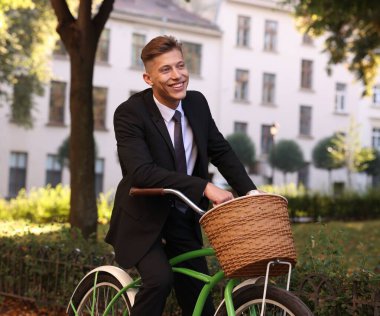 Sokakta bisiklet süren takım elbiseli bir adam.