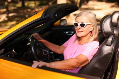 Güneş gözlüklü son sınıf öğrencisi modern Cabriolet 'i açık havada kullanıyor.