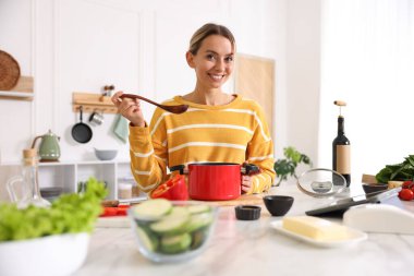 Mutfaktaki masada yemek yapan gülümseyen kadın.