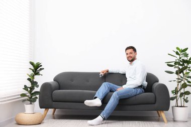 Evdeki kanepede klimalı uzaktan kumandalı bir adam. Metin için boşluk