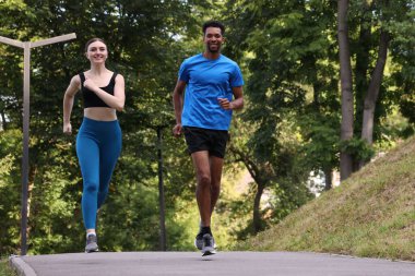 Spor kıyafetleriyle parkta koşan gülümseyen bir çift. Düşük açılı. Metin için boşluk