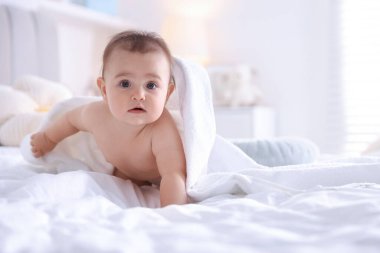 Evdeki yatakta banyo yaptıktan sonra beyaz havluyla sarılı şirin bir bebek. Mesaj atmak için yer var.