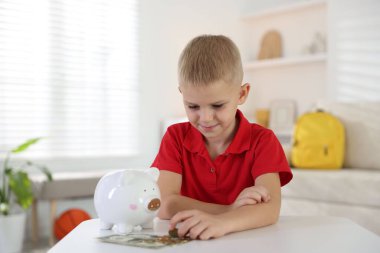 Cep harçlığı ve kumbarası olan küçük bir çocuk.