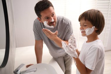 Baba oğul banyoda yüzlerine tıraş köpüğü sürüyorlar.