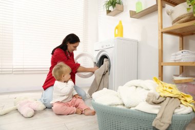 Ev hanımı ve bebeği evde çamaşır yıkıyor.