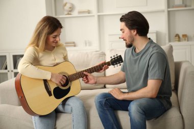 Evdeki kanepede gitar çalmayı öğreten öğretmen.