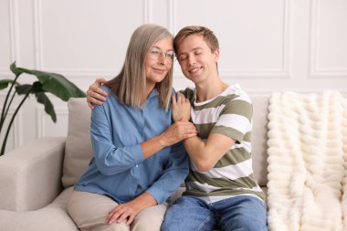 Mutlu oğul ve annesi evdeki kanepede birlikte vakit geçiriyorlar.