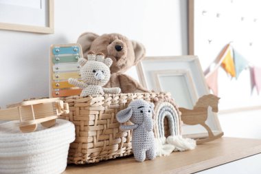 Beyaz duvarın yanındaki ahşap masada farklı oyuncaklar ve dekorlar.