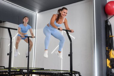Spor salonundaki mini egzersiz trambolinlerinde zıplayan genç kadınlar, düşük açı.