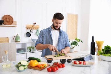 Yemek pişirme süreci. Genç adam mutfakta salatalık kesiyor.
