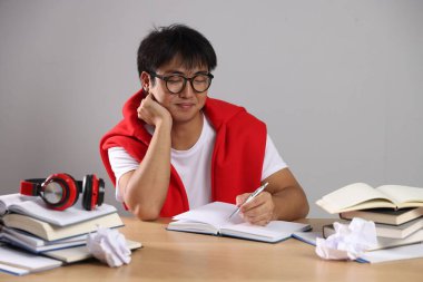 Kalem ve kitaplarla dolu bir öğrenci Gri Duvar 'ın yanındaki tahta masada sınava hazırlanıyor.