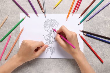 Gri masada çiçek çizen kadın, üst manzara.