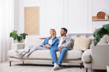 Evdeki koltukta klimalı uzaktan kumandalı bir çift.