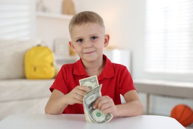 Beyaz masada cep harçlığı tutan küçük çocuk.