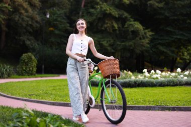 Parkta bisikletini gezdiren mutlu kadın.