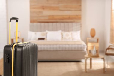 Hotel room with comfortable furniture and guest suitcase, selective focus