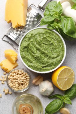 Taze pesto sosu kasede ve malzemeler açık gri masada, düz yerde.