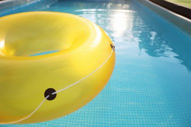 Yellow inflatable ring in swimming pool outdoors, closeup. Space for text