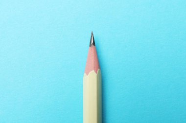 Açık mavi arkaplanda keskin bir grafit kalem, üst görünüm