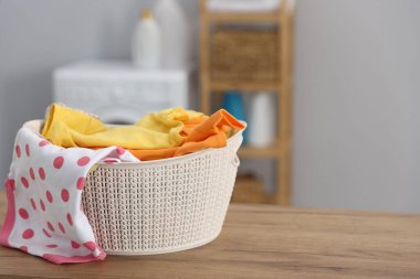 Laundry basket with clean baby clothes on wooden table indoors. Space for text