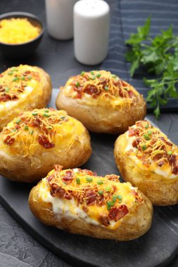 Lezzetli fırında patatesler siyah masada, yakın plan.