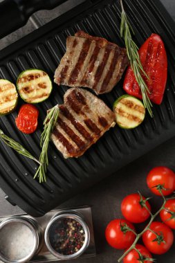 Biftek, sebze ve biberiyeli elektrikli ızgara.