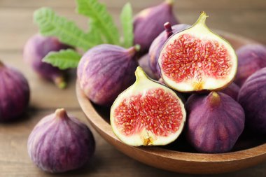 Taze incir ve yeşil yaprak ahşap masada, yakın plan.