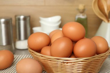 Hasır sepetteki çiğ tavuk yumurtaları tezgahın üstünde, yakın plan.