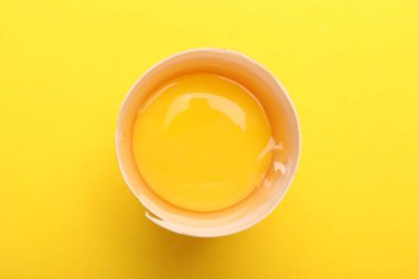 Sarı arka planda kırık bir tavuk yumurtası.