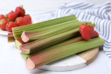 Taze ravent sapları ve çilekler beyaz masada, yakın plan.