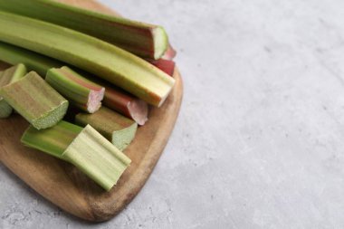 Fresh ripe rhubarb on light grey table, closeup. Space for text