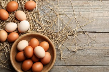 Tabakta çiğ tavuk yumurtası ve ahşap masada saman, düz. Metin için boşluk