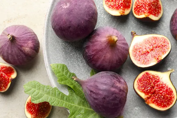 Taze incir ve yeşil yaprak. Gri masa, üst manzara.