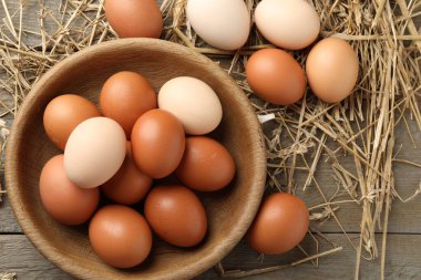 Tabakta çiğ tavuk yumurtası ve ahşap masada saman, düz. Metin için boşluk