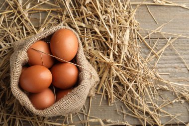Çuval çuvalında çiğ tavuk yumurtası ve ahşap masada saman, üst manzara. Metin için boşluk
