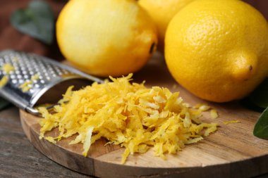 Lemon zest, fresh fruits and grater on wooden table, closeup
