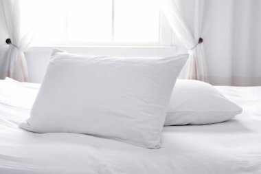 Pencerenin yanında yumuşak yastıklı modern yatak