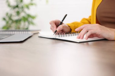 İçerideki masada dizüstü bilgisayarla sınav sırasında not alan kadın, yakın plan.