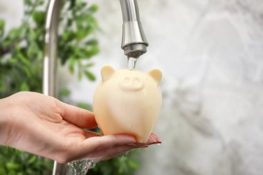 Su tasarrufu konsepti. Kumbarayı musluğun altında tutan kadın, yakın plan.