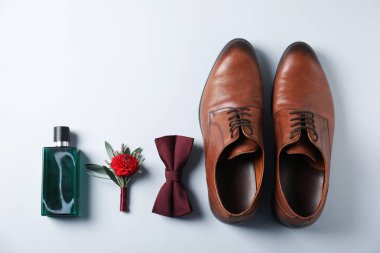 Flat lay composition with stylish boutonniere and shoes on light grey background, space for text