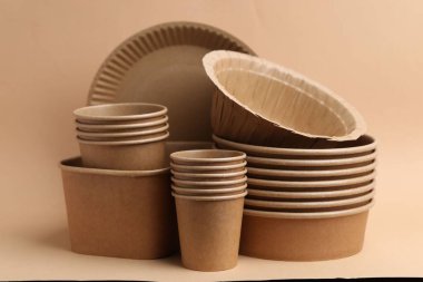 Set of disposable tableware on dark beige background, closeup