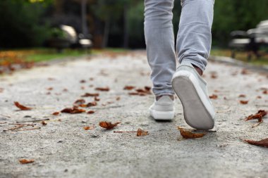 Havalı spor ayakkabılı bir adam asfaltta yürüyor, yakın plan. Metin için boşluk