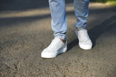 Havalı spor ayakkabılı bir adam asfaltta yürüyor, yakın plan. Metin için boşluk