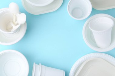 Açık mavi arka planda tek kullanımlık plastik sofra takımı, düz. Metin için boşluk