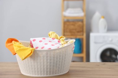 Laundry basket with clean baby clothes on wooden table indoors. Space for text