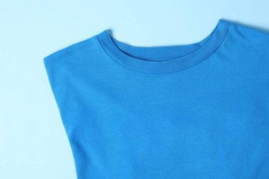 T-shirt on light blue background, top view. Mockup for design