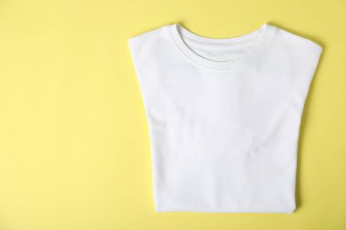 White t-shirt on yellow background, top view. Mockup for design